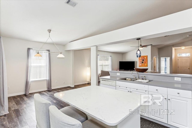 kitchen featuring a sink, visible vents, open floor plan, vaulted ceiling, and a center island