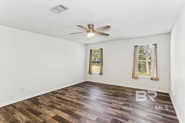 spare room featuring visible vents, dark wood-type flooring, ceiling fan, a textured ceiling, and baseboards