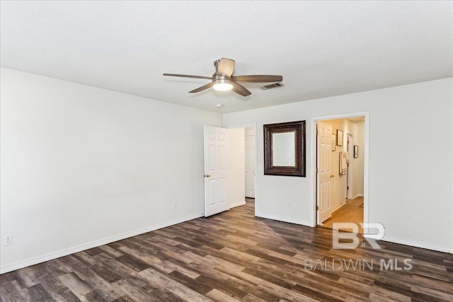 unfurnished room with dark wood-type flooring, visible vents, a textured ceiling, and baseboards