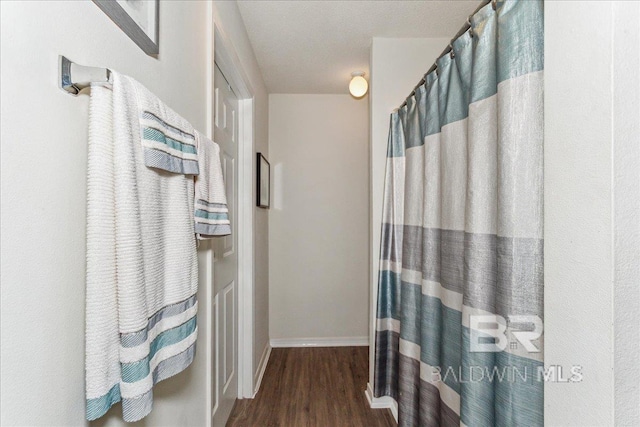 bathroom featuring a shower with curtain, baseboards, and wood finished floors