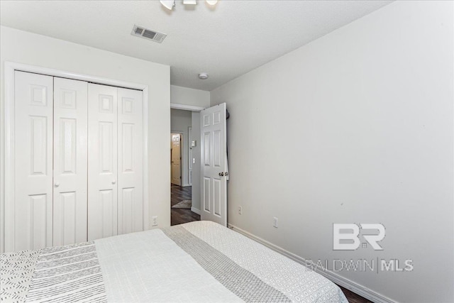 bedroom featuring baseboards, a textured ceiling, visible vents, and a closet