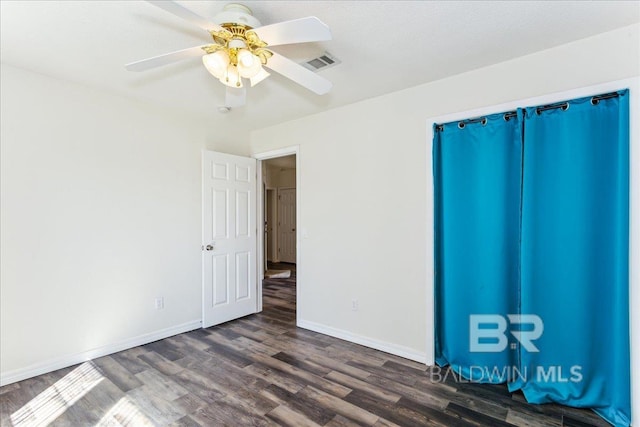 unfurnished bedroom featuring a ceiling fan, visible vents, dark wood finished floors, and baseboards