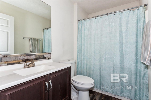 bathroom with toilet, a textured ceiling, wood finished floors, and vanity