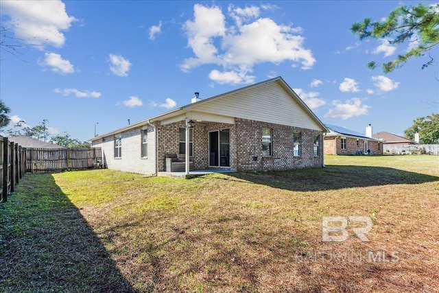 back of house featuring brick siding, a fenced backyard, a patio area, and a yard