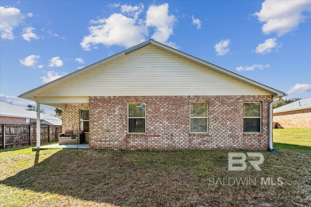 back of property with brick siding, fence, a patio, and a yard