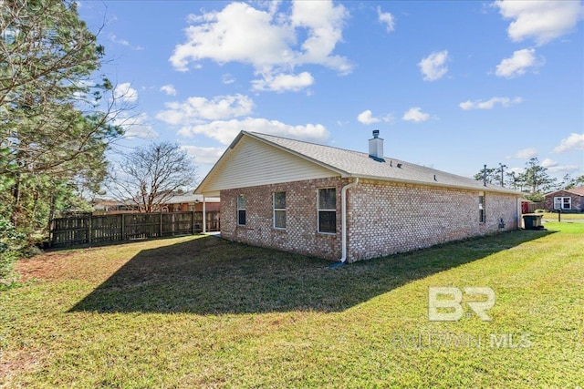 view of home's exterior with brick siding, a lawn, a chimney, and fence