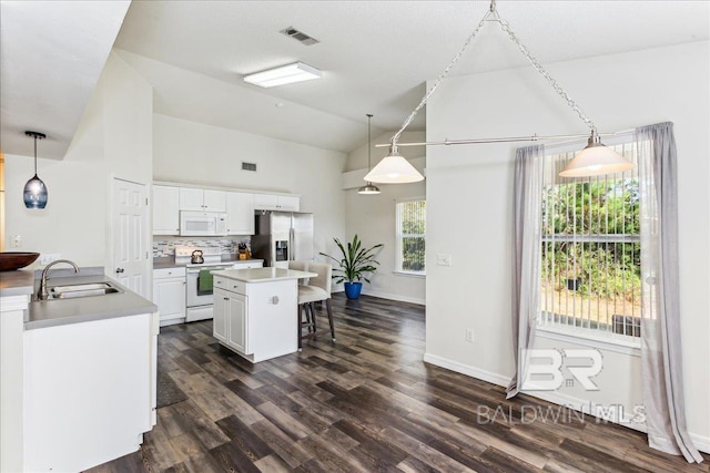 kitchen with dark wood-style floors, white cabinetry, a sink, white appliances, and a kitchen breakfast bar