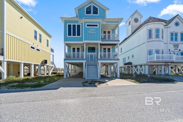 1402 W Dune Dr, Gulf Shores, AL 36542 - coastal inspired home featuring concrete driveway, a carport, board and batten siding, and stairs