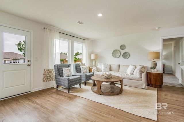 living area featuring baseboards, visible vents, and wood finished floors