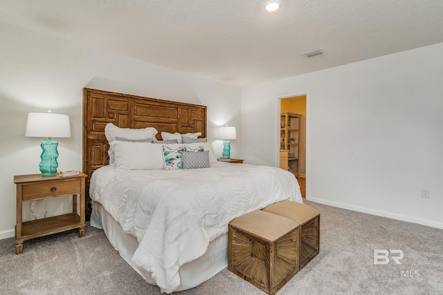 bedroom with light carpet, visible vents, baseboards, and a textured ceiling