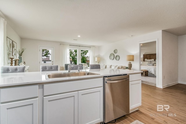 kitchen with a sink, open floor plan, dishwasher, and light countertops