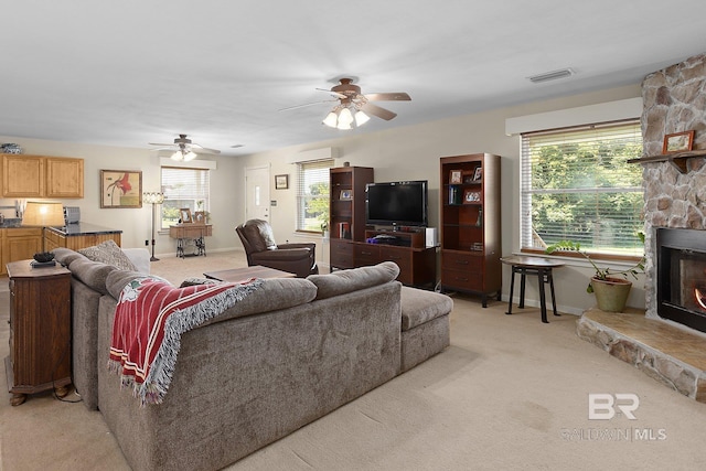 24675 Ulrich Ln, Elberta, AL 36530 - living room with light colored carpet, a wall mounted air conditioner, a fireplace, ceiling fan, and plenty of natural light