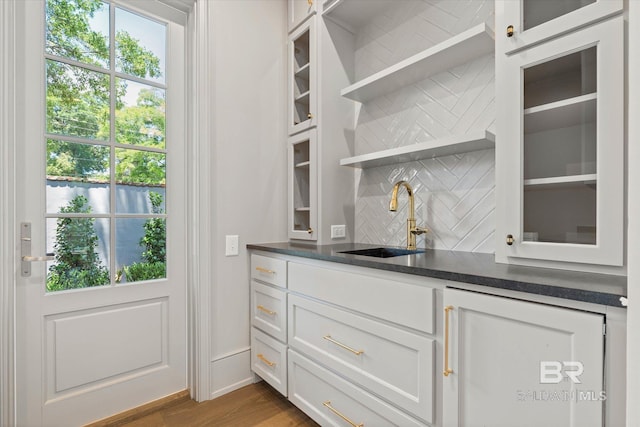 indoor wet bar featuring backsplash, dark wood-style flooring, and baseboards