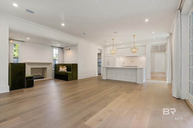 unfurnished living room with a fireplace, light wood-style floors, crown molding, recessed lighting, and baseboards