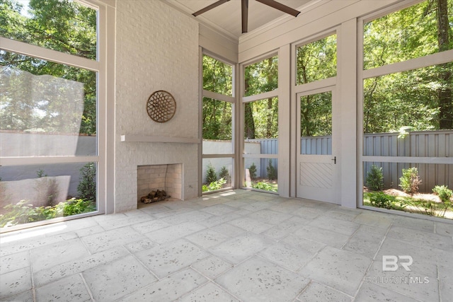 unfurnished sunroom featuring a fireplace, ceiling fan, and healthy amount of natural light