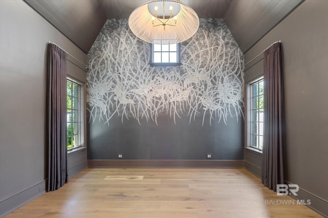 unfurnished room featuring vaulted ceiling, wood finished floors, an accent wall, wooden ceiling, and baseboards