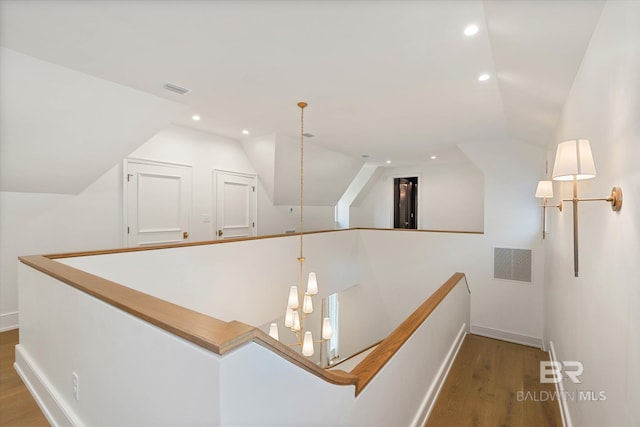 hallway featuring an upstairs landing, vaulted ceiling, wood finished floors, baseboards, and recessed lighting