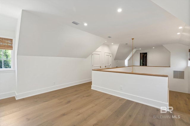 additional living space featuring vaulted ceiling, light wood-style flooring, recessed lighting, and baseboards