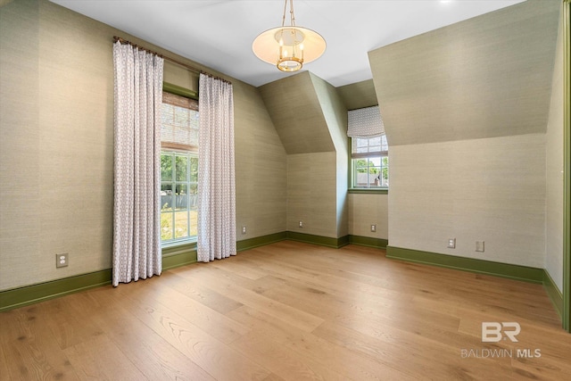 bonus room featuring wood finished floors, a chandelier, and baseboards