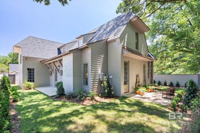 view of home's exterior with a patio, brick siding, and a shingled roof