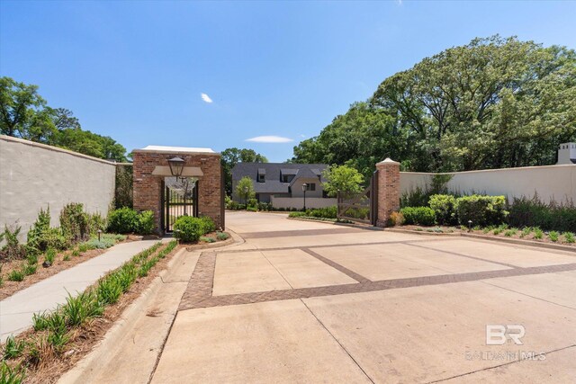 view of concrete street featuring a gate, curbs, a gated entry, and sidewalks