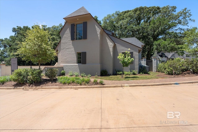 view of side of property featuring brick siding and fence