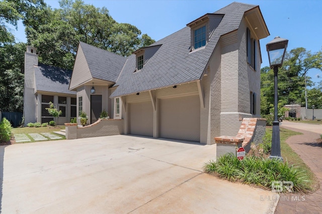 view of front of property featuring concrete driveway, a chimney, and a garage