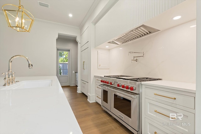 kitchen with double oven range, a sink, ornamental molding, light countertops, and wood finished floors