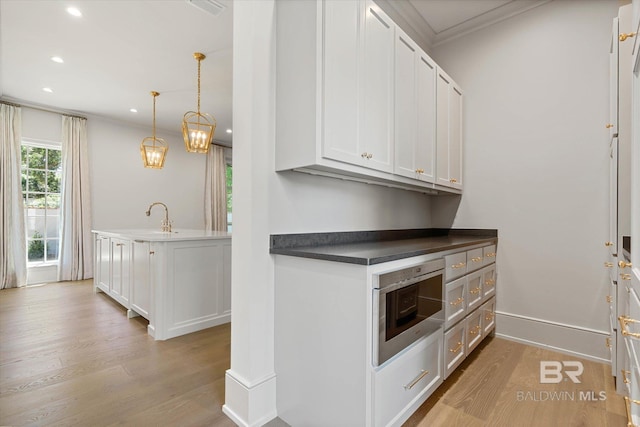 kitchen with crown molding, light wood-style floors, recessed lighting, a sink, and white cabinets