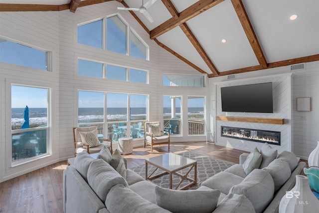 living room with ceiling fan, beam ceiling, high vaulted ceiling, a fireplace, and hardwood / wood-style floors