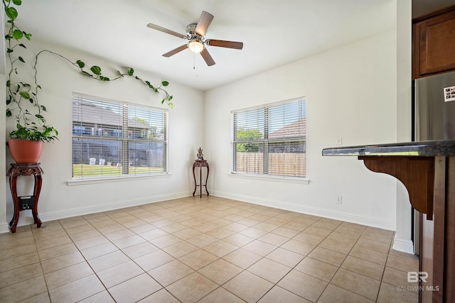 unfurnished room with plenty of natural light, ceiling fan, light tile patterned floors, and baseboards