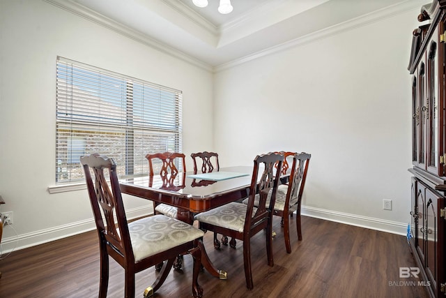 dining space featuring dark wood finished floors, a raised ceiling, baseboards, and crown molding