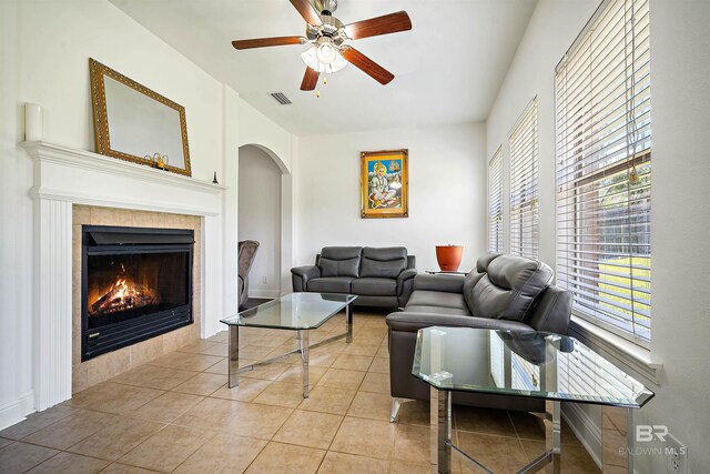 living area with healthy amount of natural light, a fireplace, a ceiling fan, and arched walkways