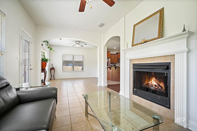 living area with a ceiling fan, light tile patterned floors, and arched walkways
