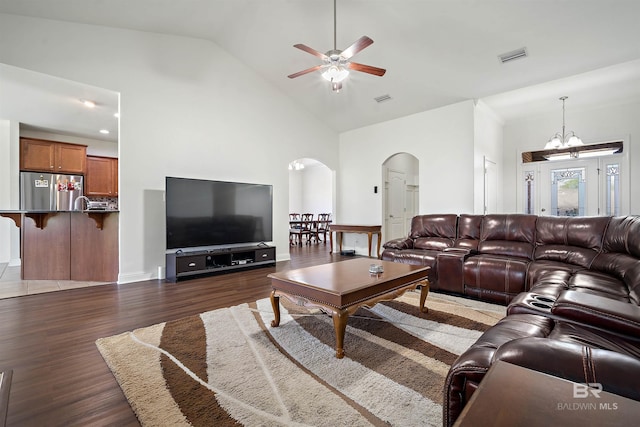 living room with arched walkways, wood finished floors, a ceiling fan, high vaulted ceiling, and a chandelier