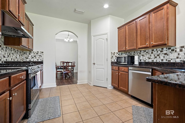 kitchen with dishwasher, gas range, under cabinet range hood, arched walkways, and light tile patterned flooring