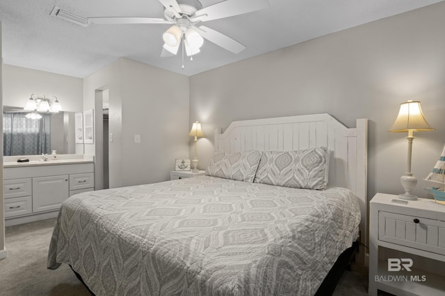 carpeted bedroom with sink, ensuite bath, and ceiling fan