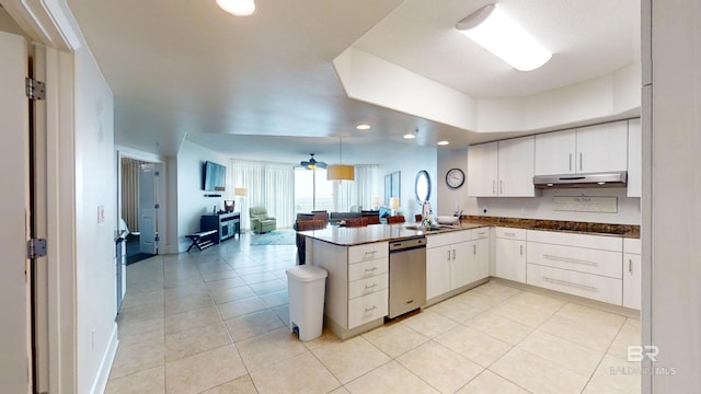 kitchen with a peninsula, dishwasher, dark countertops, under cabinet range hood, and open floor plan