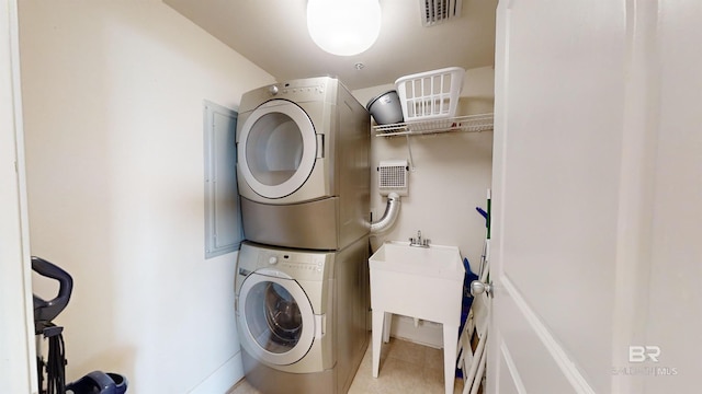 clothes washing area featuring tile patterned floors, a sink, stacked washing maching and dryer, laundry area, and visible vents