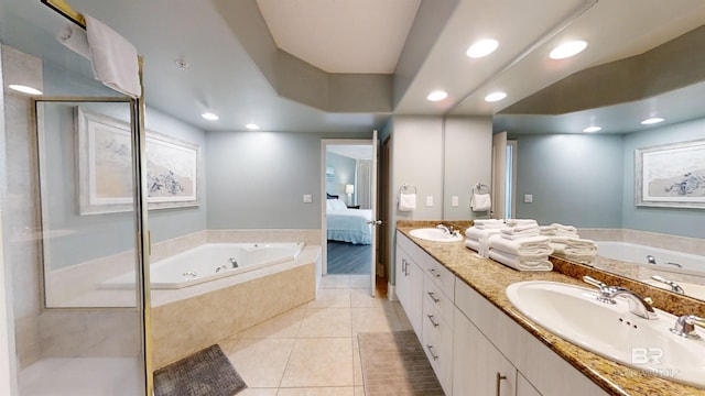ensuite bathroom with tile patterned flooring, a sink, a jetted tub, and connected bathroom