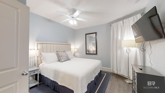 bedroom with a ceiling fan and dark wood-style flooring