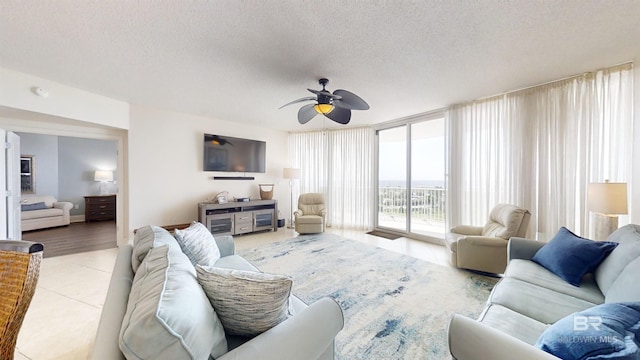 living area featuring light tile patterned flooring, a textured ceiling, floor to ceiling windows, and a ceiling fan