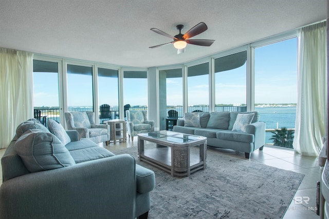 tiled living room with expansive windows, a water view, and a textured ceiling