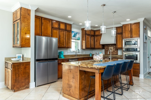 kitchen featuring an island with sink, decorative light fixtures, light stone counters, and stainless steel appliances