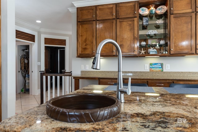 kitchen with light tile flooring, crown molding, sink, and light stone counters