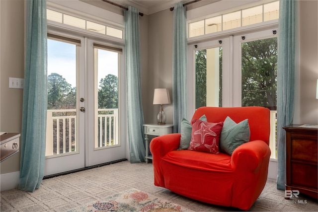 sitting room featuring plenty of natural light, french doors, crown molding, and light carpet