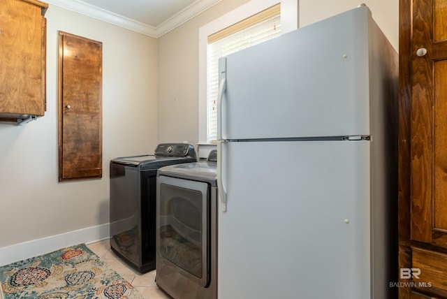 clothes washing area featuring a healthy amount of sunlight, separate washer and dryer, ornamental molding, and light tile floors