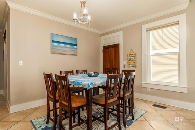 dining room with a chandelier, light tile floors, and crown molding