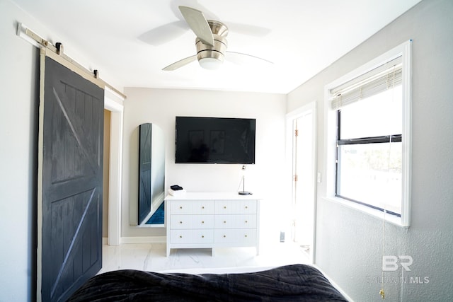 unfurnished bedroom with multiple windows, a barn door, and ceiling fan