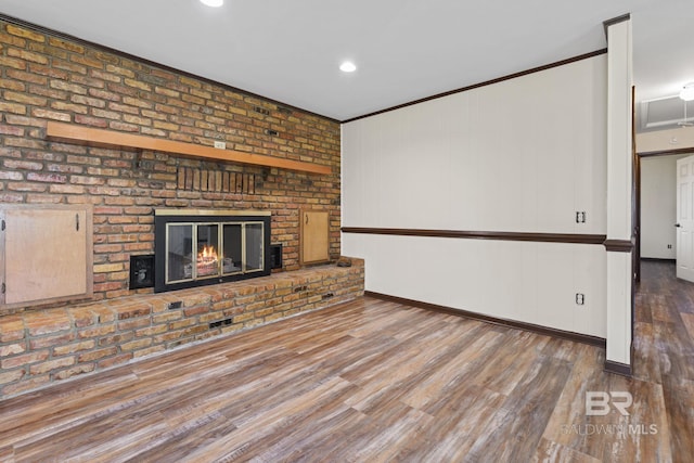 unfurnished living room featuring a brick fireplace, brick wall, crown molding, and hardwood / wood-style floors